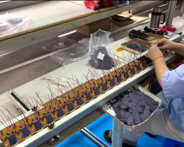 Worker assembling and testing hotel telephones on the factory production line